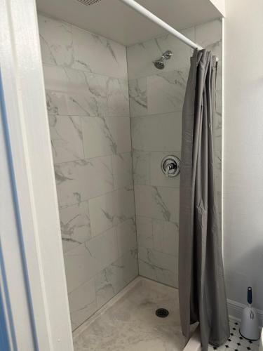 ducha con paredes de mármol blanco y cortina de ducha en The Hotel Redland, en Homestead