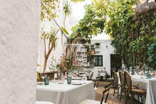 a table with white table cloths and chairs on a patio at Doña Lola Rooms in Conil de la Frontera