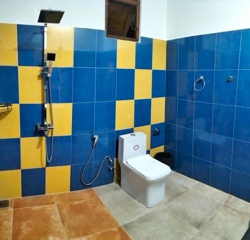 een badkamer met een toilet en blauwe en gele tegels bij Kithaya Ella in Ella