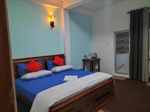 a bedroom with a blue bed with red pillows at Kithaya Ella in Ella