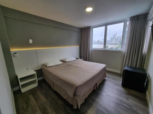 a hotel room with a bed and a large window at Marambaia Hotel e Convenções in Balneário Camboriú