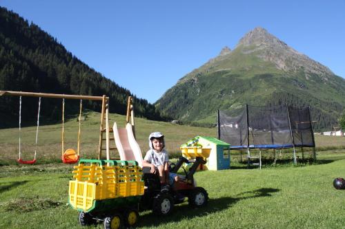a child sitting in a toy car in a field at Apart Renate in Galtür