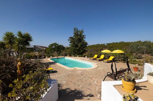 a swimming pool with yellow lounge chairs and a swimming pool at Ninho Da Poupa in Serpa