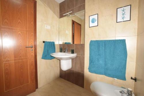 een badkamer met een wastafel, een toilet en blauwe handdoeken bij Apartamento Antia in Fisterra