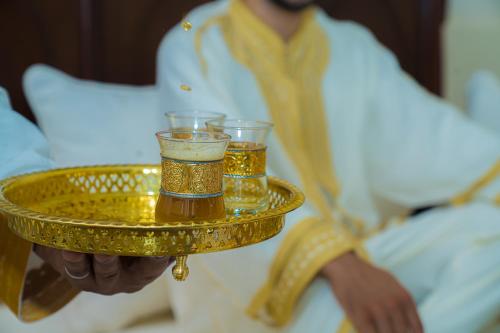 a man holding a gold tray with two glasses on it at Riad Dar Zaouia in Marrakech
