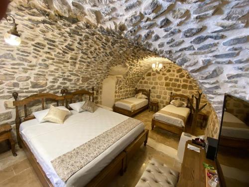 a bedroom with two beds and a stone wall at Hanedan Konağı Butik Otel in Yaylacık