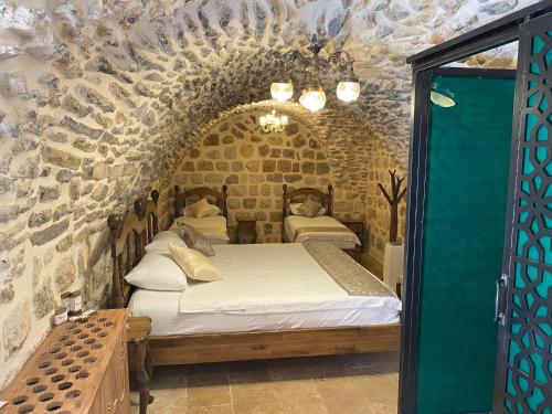 a bedroom with two beds in a stone wall at Hanedan Konağı Butik Otel in Yaylacık