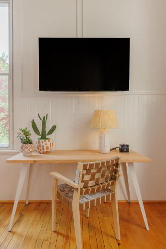 a table with a chair and a television on a wall at Fire Station One Boutique Hotel in Roanoke