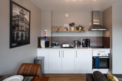 a kitchen with white cabinets and a counter top at High Street Town House in Manchester