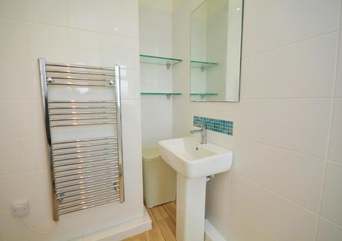 a white bathroom with a sink and a mirror at Sandhills 9 in Padstow