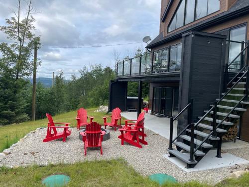 a group of red chairs and tables outside of a house at Au Coin Du Belvédère in Saint Come
