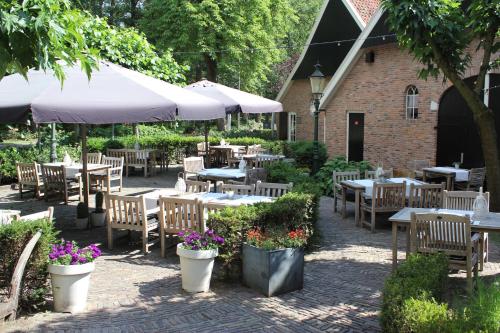 a patio with tables and chairs with flowers and umbrellas at Vakantiehuis de Bakspieker in Haaksbergen