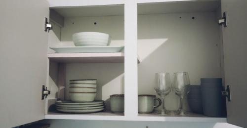 um armário branco com pratos, copos e pratos em Urban Lodgings Two @ Roosevelt 457 em San Juan