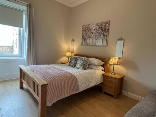 a bedroom with a bed with two lamps and a window at Luxury Victorian spacious flat in Glasgow