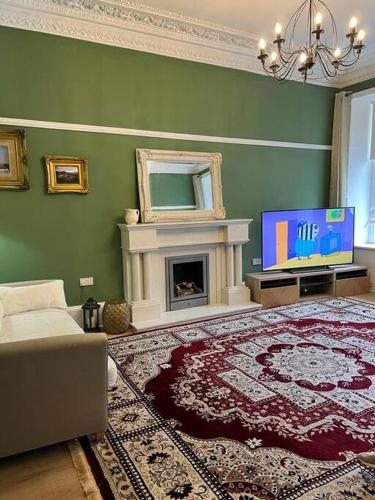 a living room with a fireplace and a tv at Luxury Victorian spacious flat in Glasgow