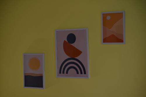 a wall with three pictures on a yellow wall at Megdan - stan na dan in Užice