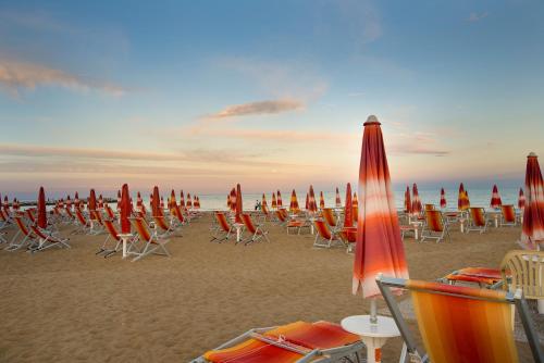 un montón de sillas y sombrillas en una playa en Centro Vacanze Opera Nascimbeni, en Cavallino-Treporti