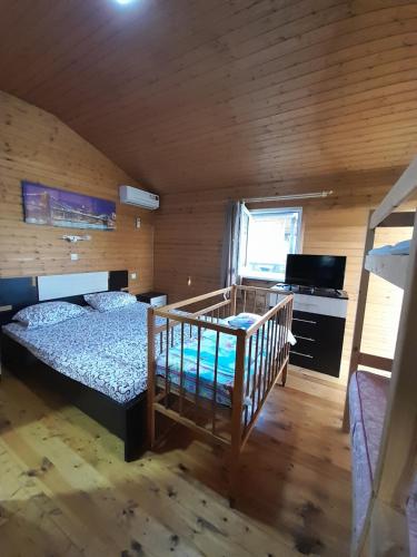 a bedroom with a bed and a crib in a room at Отель Домик у реки Хипста in Gudauta