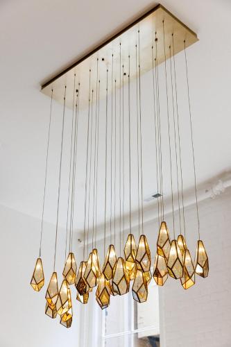 a cluster of gold lights hanging from a ceiling at Fire Station One Boutique Hotel in Roanoke