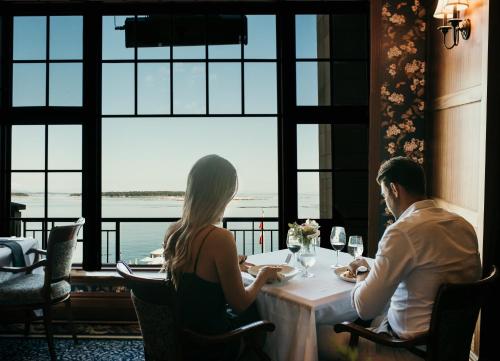 a man and woman sitting at a table in a restaurant at Oak Bay Beach Hotel in Victoria