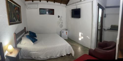 a small bedroom with a bed and a chair at Pousada Estalagem Paraty in Paraty