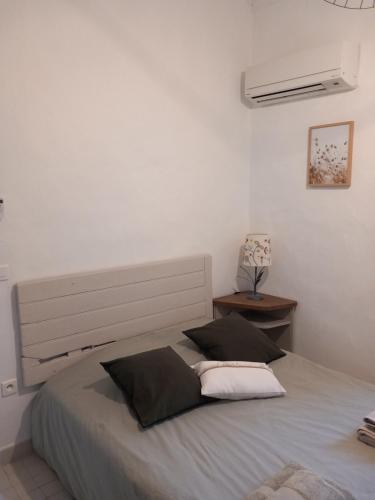 - une chambre blanche avec un lit et deux oreillers dans l'établissement Le Petit Mas des Alpilles en Provence, à Saint-Étienne-du-Grès