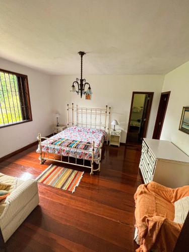 um quarto com uma cama e piso em madeira em Chale das hortensias em Petrópolis