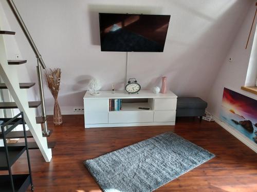 a living room with a white cabinet and a clock at Ferienhaus Elbliebe - kleine Hunde bis 25 cm willkommen in Dannenberg