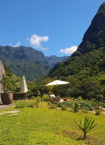 a patio with an umbrella and chairs with mountains in the background at Terrabona Nature & Vineyards in Boaventura