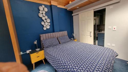 ein Schlafzimmer mit einem Bett und einer blauen Wand in der Unterkunft Glebe House, Private entrance, free parking on drive, Self check in, Netflix in Ashford