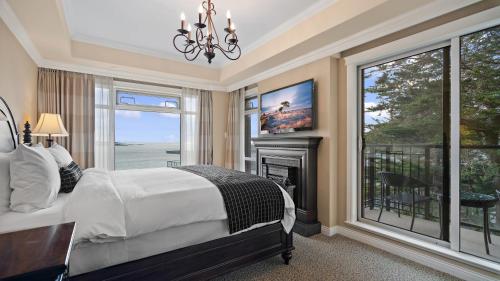 a bedroom with a bed and a fireplace and a window at Oak Bay Beach Hotel in Victoria
