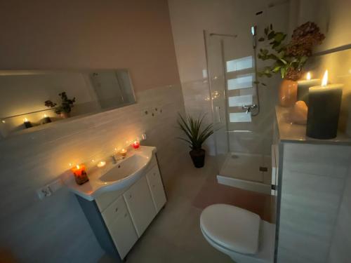 een badkamer met een wastafel, een toilet en kaarsen bij Apartament III w Centrum - Winda - 50 metrów od Starego Rynku in Kościerzyna