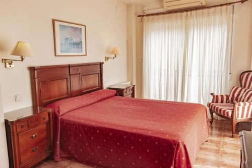 a bedroom with a bed and a chair and a window at Hotel Tàrbena in Tárbena