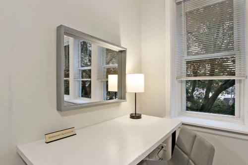 einen weißen Schreibtisch mit einer Lampe und zwei Fenstern in der Unterkunft Modern & Furnished 2BR Apt with In-unit Laundry - Sunnyside 2E in Chicago