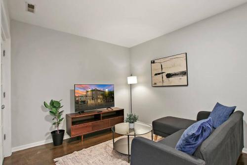 a living room with a couch and a flat screen tv at Modern & Furnished 2BR Apt with In-unit Laundry - Sunnyside 2E in Chicago
