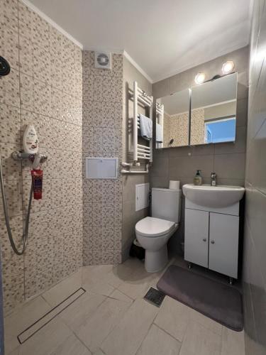 a bathroom with a toilet and a sink and a shower at Kenzia Prive in Bucharest