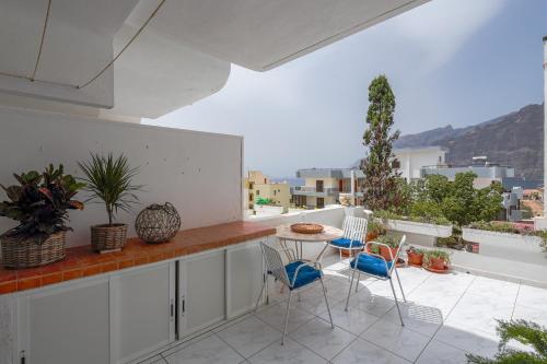 um pátio com uma mesa e cadeiras numa varanda em One-bedroom with views of Los Gigantes em Santiago del Teide
