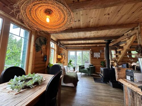 ein Wohnzimmer mit einer Holzdecke und einem Tisch in der Unterkunft Le Ti Moose - Les Chalets Spa Canada in La Malbaie