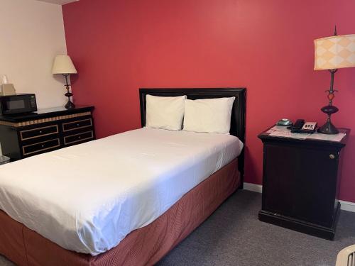 a bedroom with a bed and a red wall at Ramada by Wyndham Williston in Williston