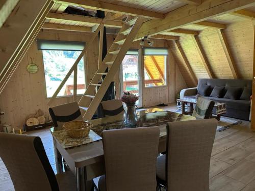 a living room with a table and chairs and a staircase at Cabanutze Satic in Rucăr
