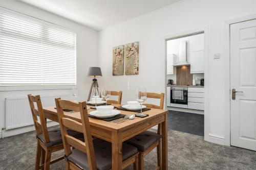 een keuken en eetkamer met een houten tafel en stoelen bij Dacy Lodge - Anfield Apartments in Liverpool