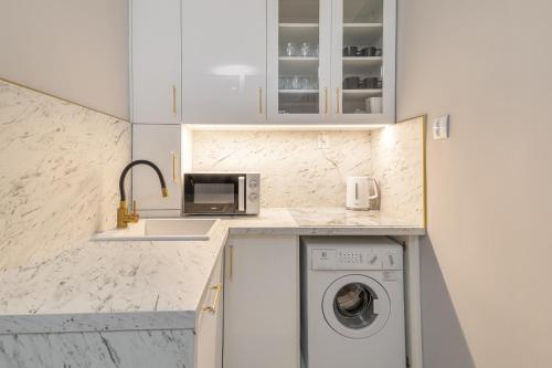a white kitchen with a washing machine and a sink at Gold Glamour Apartment Sopot z dwoma sypialniami, duzy balkon in Sopot