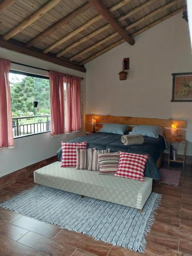 une chambre avec un lit et un canapé avec des oreillers dans l'établissement Chalé Canto Mundo, à Brazópolis