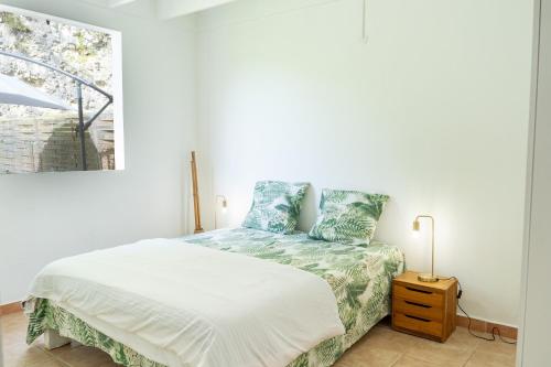 Habitación blanca con cama y ventana en Villa Le Boursoie, villa au calme avec jacuzzis., en Les Abymes