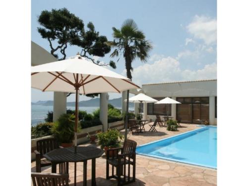 einen Pool mit Tischen, Stühlen und einem Sonnenschirm in der Unterkunft Seaside Hotel Geibousou - Vacation STAY 92572v in Shima