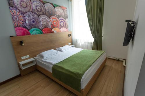 een slaapkamer met een bed met een schilderij aan de muur bij Koisha in Bisjkek