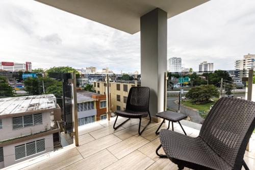 a balcony with two chairs and a view of a city at Avila Suites in San Juan