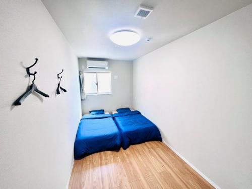 sypialnia z niebieskim łóżkiem w białej ścianie w obiekcie GUEST House color - Vacation STAY 60868v w Osace