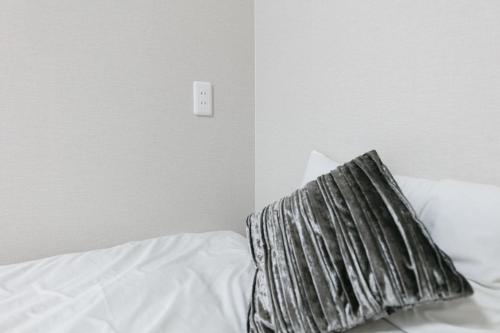 łóżko z poduszką i przełącznikiem na ścianie w obiekcie GUEST House color - Vacation STAY 60868v w Osace