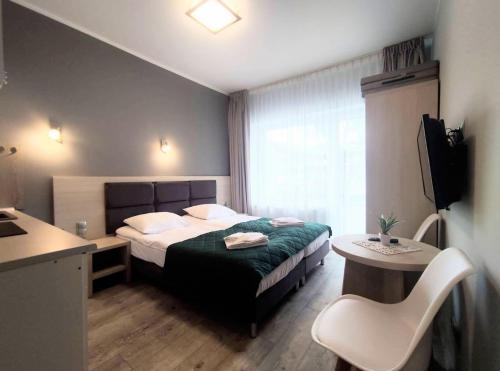 a hotel room with a bed and a desk and a television at Apartament Dominikana 13 in Sianozety